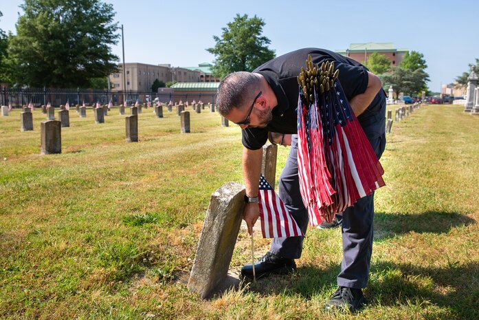 Norfolk Naval Shipyard Veteran Employee Readiness Group President Nicholas Boyle and his son Connor Boyle place flags on the graves of fallen service members during the annual flag placement ceremony at the Captain Ted Conaway Memorial Naval Cemetery in Naval Medical Center Portsmouth (NMCP) May 27.