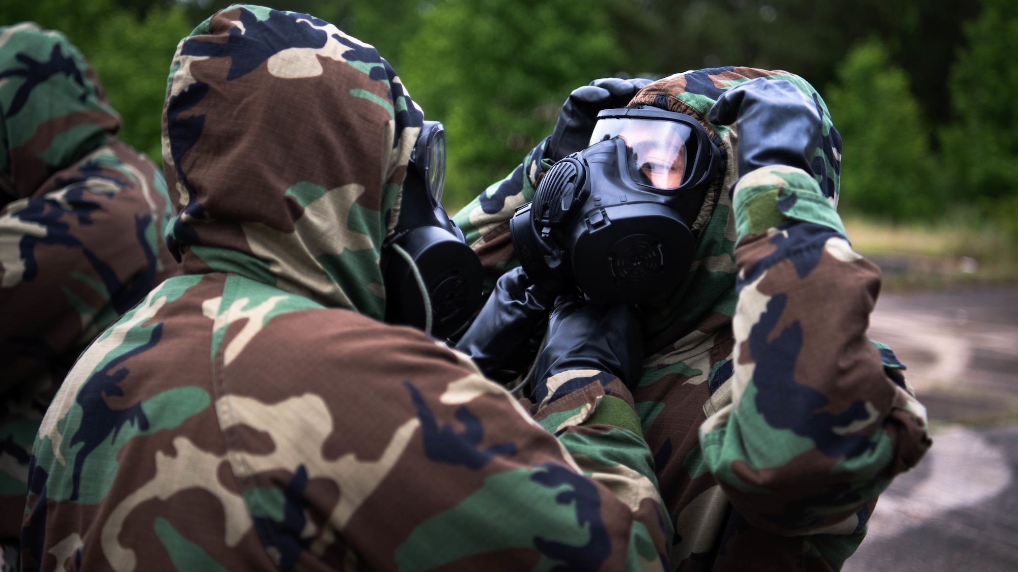 Airmen from the 2nd Civil Engineer Squadron perform "buddy checks'' after donning mission oriented protective posture gear during a 2nd CES training exercise at Barksdale Air Force Base, Louisiana, May 20, 2021. The exercise showcased contingency skills such as: land navigation, self-aid buddy care and chemical, biological, radiological and nuclear preparedness. (U.S. Air Force photo by Senior Airman Jacob B. Wrightsman)
