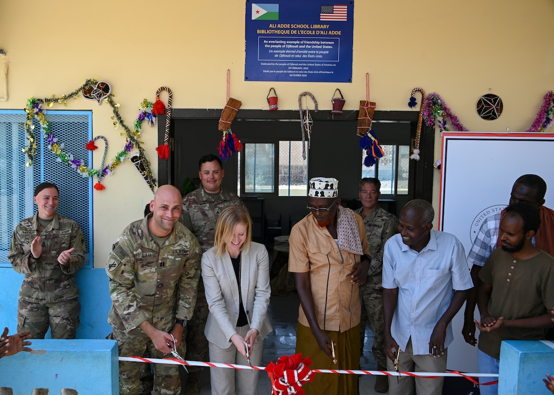 U.S. Army Reserve Capt. Sultan Durzi, left, team chief of Civil Affairs East Africa Southern European Task Force Africa, in support of Combined Joint Task Force-Horn of Africa, Liz Canellakis, center left, public diplomacy officer for the U.S. Embassy, Hassan Samreh, right center, chief of Ali Adde village, and Mahamoud Robleh, right, director of Ali Adde School, cut the ribbon during the inauguration ceremony of the new Ali Adde school library in Ali Adde, Djibouti, May 27, 2021. The library marks the third U.S.-funded library completed within Djibouti with more in the works.