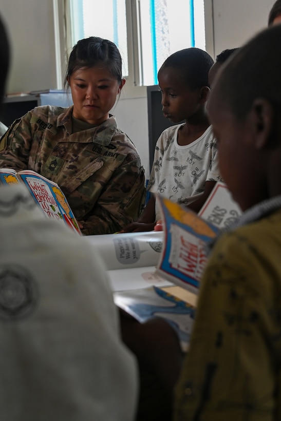 U.S. Army Reserve Master Sgt. Bethany Bedard, team sergeant of Civil Affairs East Africa Southern European Task Force Africa, in support of Combined Joint Task Force-Horn of Africa, reads with a child at the new Ali Adde school library in Ali Adde, Djibouti, May 27, 2021. The library dedication ceremony celebrated the completion and handover of the U.S.-funded construction project.