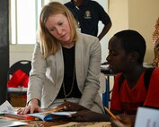 Liz Canellakis, public diplomacy officer for the U.S. Embassy, helps a child read English at the new Ali Adde school library in Ali Adde, Djibouti, May 27, 2021. U.S. Army Soldiers and the U.S. Embassy in Djibouti donated children's books as part of the new library, which was a U.S.-funded construction project that employed a local Djiboutian construction company.