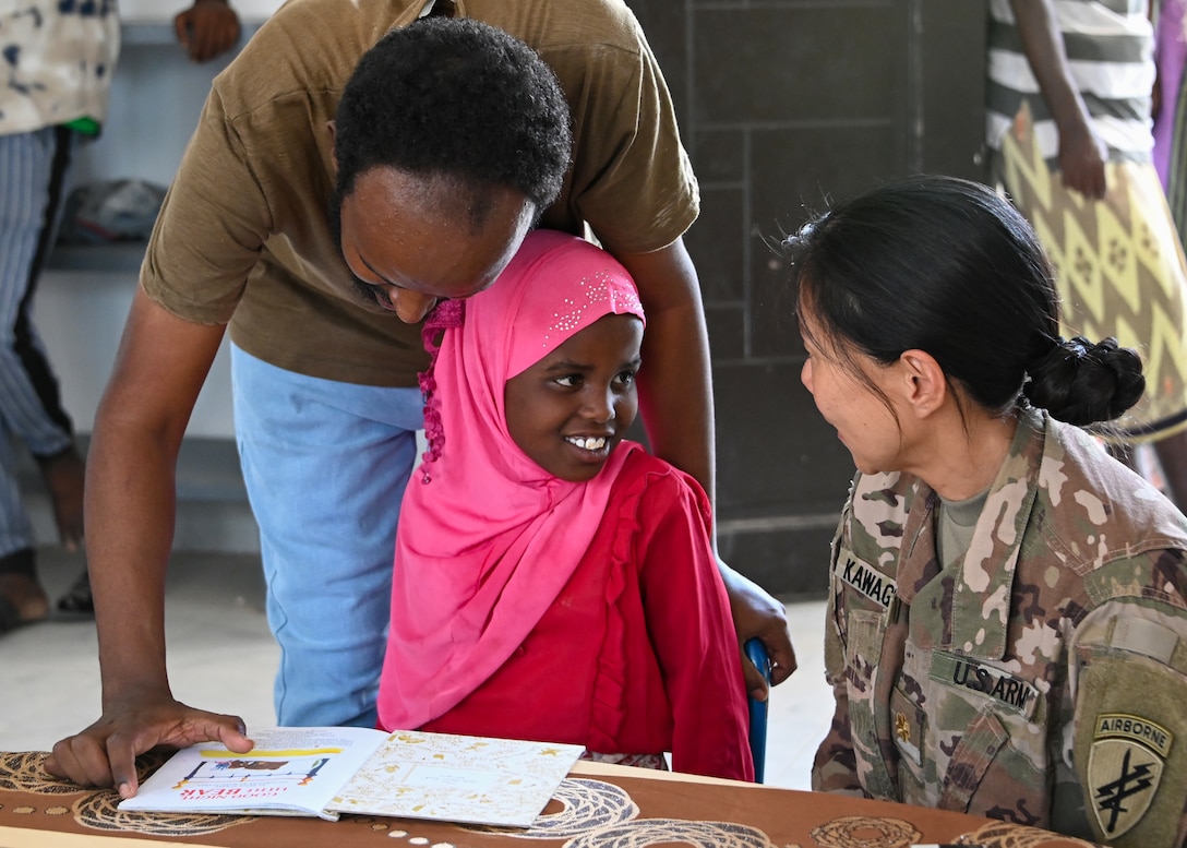 U.S. Army Reserve Maj. Sachiyo Kawaguchi, a dentist assigned to Civil Affairs East Africa Southern European Task Force Africa functional specialty team, in support of Combined Joint Task Force-Horn of Africa, reads with a child at the new Ali Adde school library, in Ali Adde, Djibouti, May 27, 2021. The new library was a U.S.-funded construction project which created local jobs and was built by a Djiboutian construction company employing Djiboutian laborers.