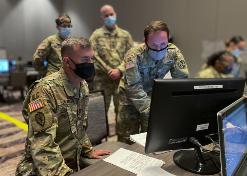 U.S. Army Reserve Spc. Kevin Maldonado (right), a signal support specialist with the 338th Medical Brigade, 3rd Medical Command Deployment Support, demonstrates his simulation operation role to Commanding General Maj. Gen. Joe Robinson, 3rd Medical Command Deployment Support, during U.S. Army North’s exercise Vibrant Response 21.