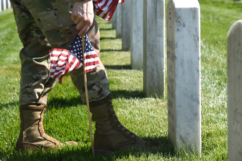 Close up of hand pushing flag into ground.