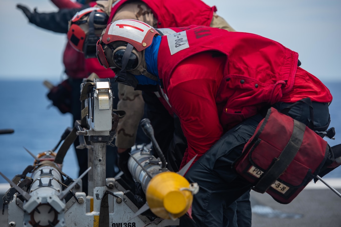 Sailors remove an AIM 9X missile from an F/A-18F Super Hornet on the flight deck of the U.S. Navy's only forward-deployed aircraft carrier USS Ronald Reagan (CVN 76).