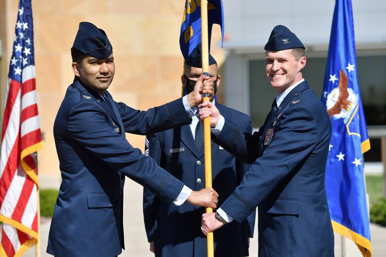 Two men holding a flag together standing outside.