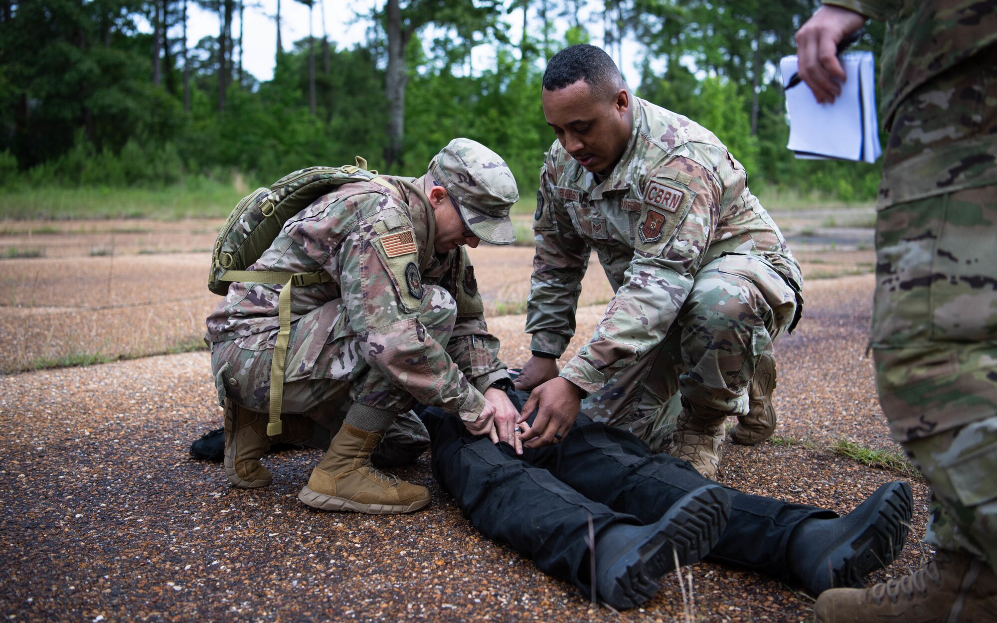 Master Sgt. Richard McGinnis. 2nd Civil Engineer Squadron commander's support staff superintendent, and Staff Sgt. Roderick R. Pearson Jr., 2nd CES emergency management plans noncommissioned officer in charge, place a tourniquet on a dummy during a 2nd CES training exercise at Barksdale Air Force Base, Louisiana, May 20, 2021. The exercise combined various contingency skills the engineers may face in a deployed environment. (U.S. Air Force photo by Senior Airman Jacob B. Wrightsman)