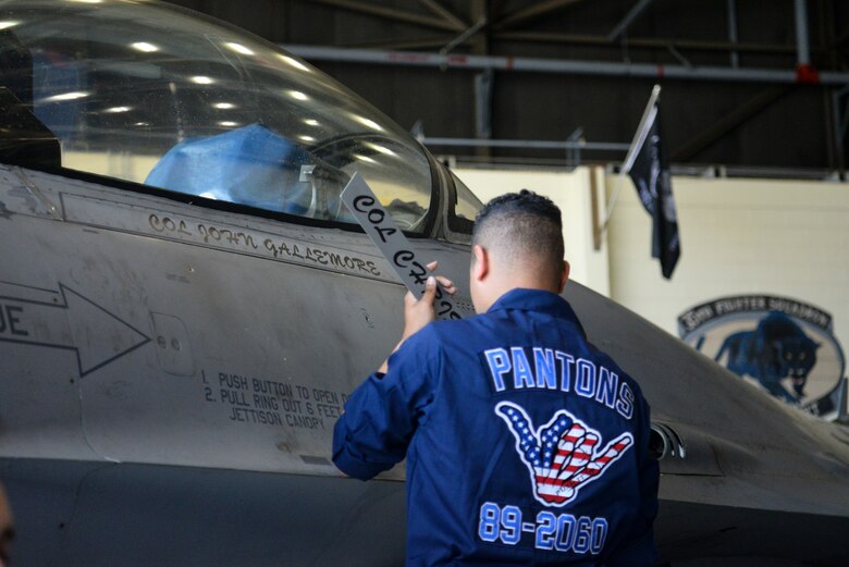 An Airman unveils a name on a jet.