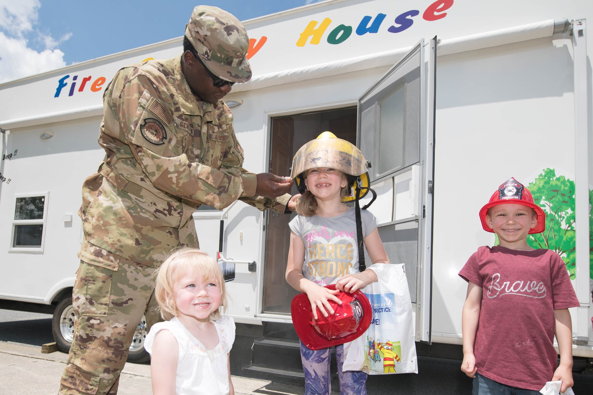 Staff Sgt. Marcus Scriven, 436th Civil Engineer Squadron crew chief, puts a firefighter helmet on Emma Peterson during the 2021 Hurricane Block Party at Dover Air Force Base, Delaware, May 27, 2021. The block party, sponsored by the 436th CES Emergency Management flight, offered attendees useful information pertaining to severe storms and hurricanes. (U.S. Air Force photo by Mauricio Campino)