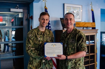 Lt. Benjamin D. Smith is presented the Navy and Marine Corps Commendation Medal as an end-of-tour award by Capt. Steven W. Antcliff, commanding officer, Naval Submarine School, aboard Naval Submarine Base New London in Groton, CT on May 19, 2021. As the Prospective Nuclear Engineering Officer (PNEO) for the Naval Submarine School, Smith ensured that over 150 office students passed the engineer examination, providing highly qualified new department heads to the submarine force. Additionally, Smith’s innovation which allowed for continued instruction with no interruption to the training pipeline during the COVID-19 pandemic. (U.S. Navy photo by Charles E. Spirtos)