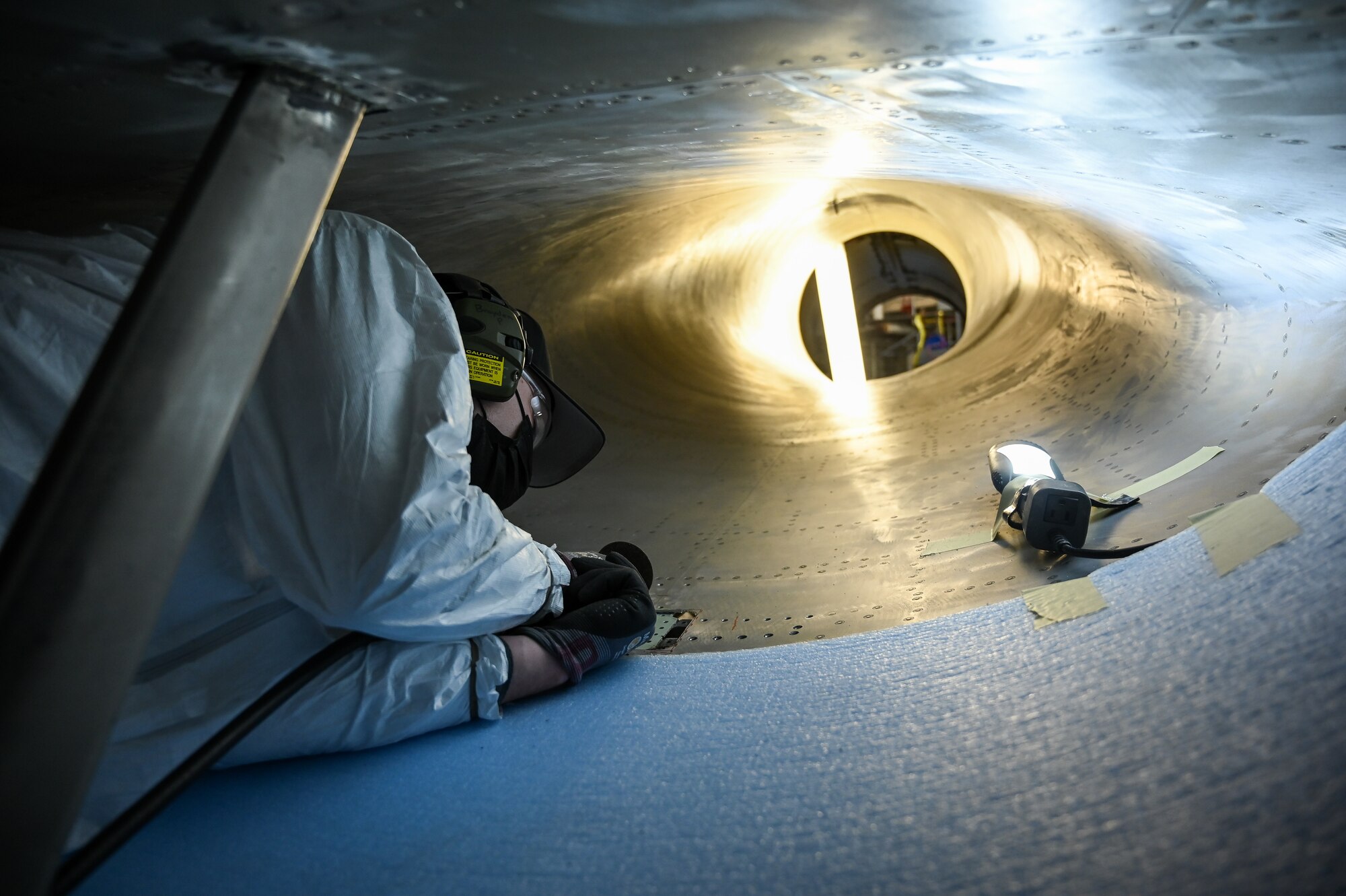 A maintainer inside an F-16 intake.