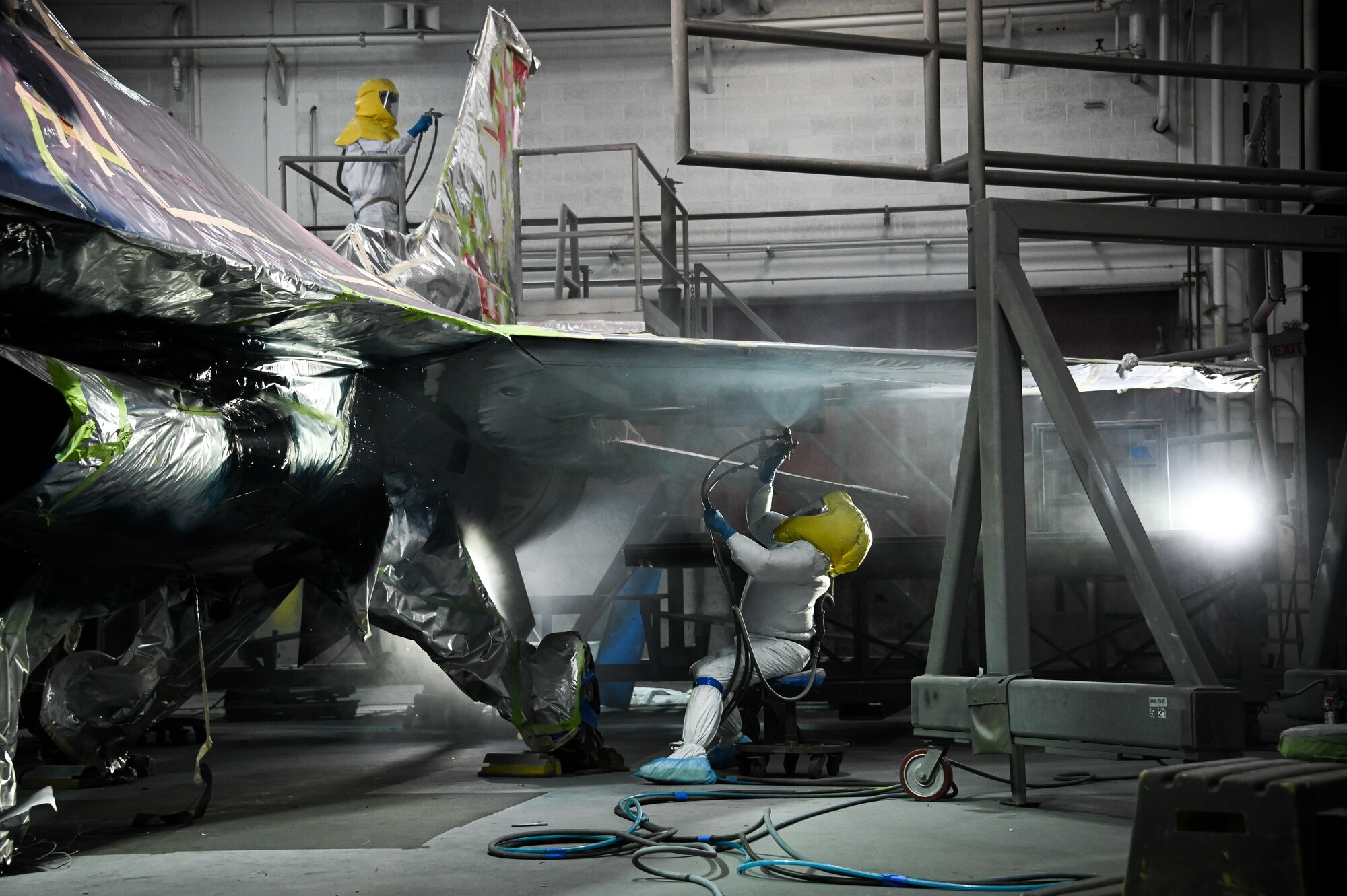 Two painters paint an F-16.