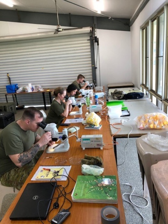 Australian Defence Forces scientists conduct malaria microscope in a field laboratory. b