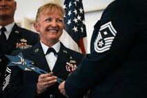 Woman in dress blues receives wand.