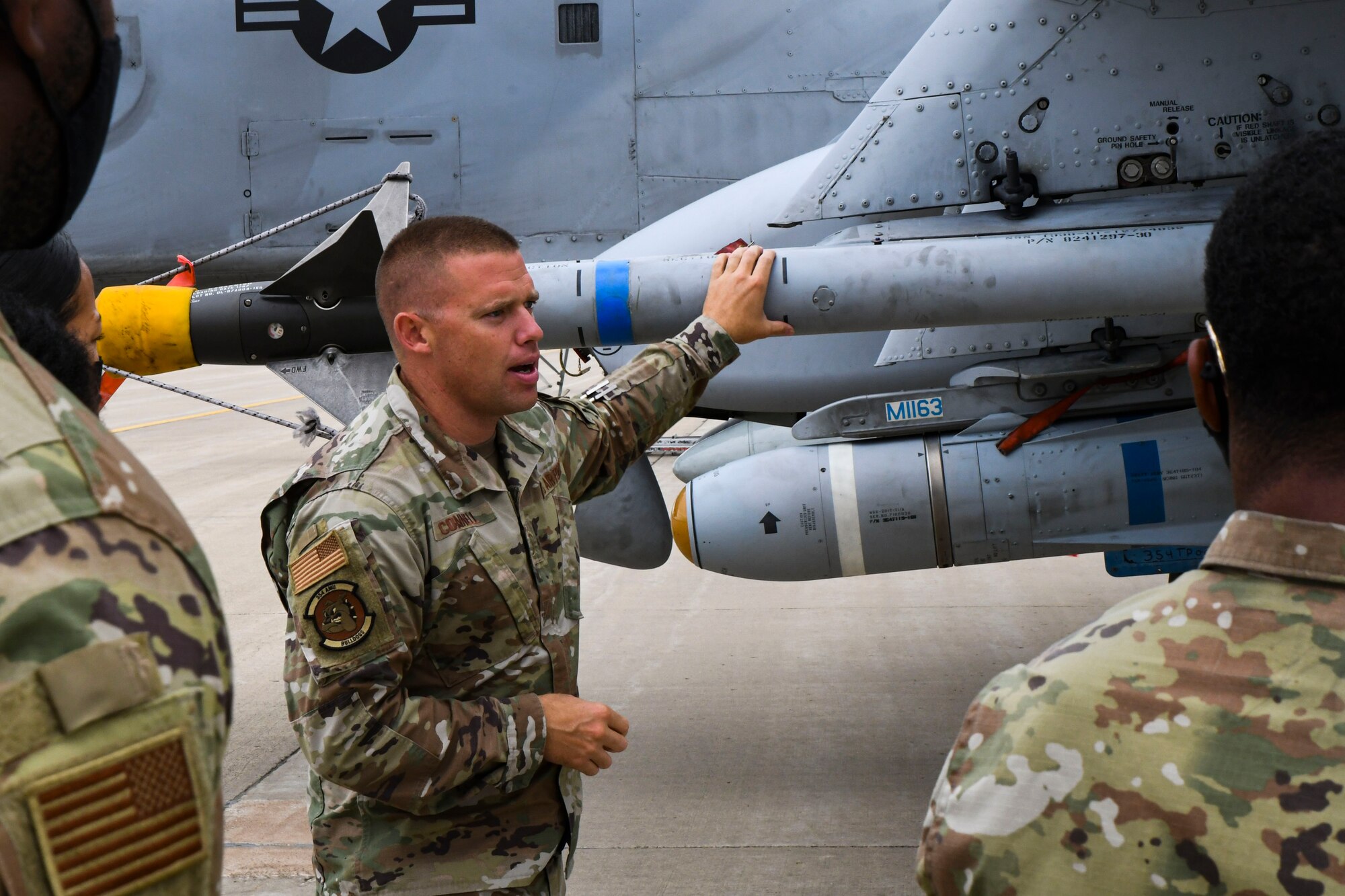 A photo of an airman talking next to a jet
