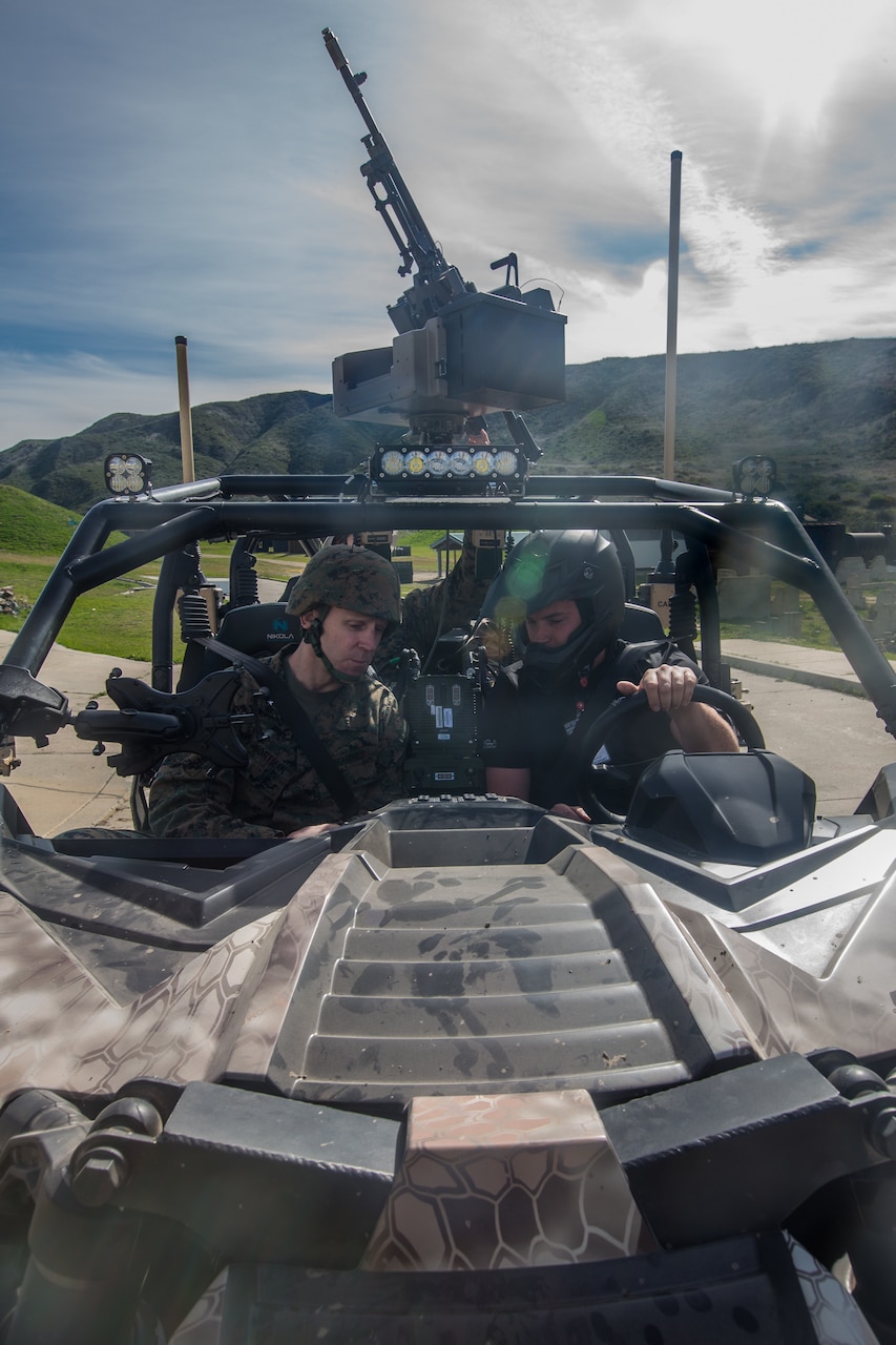 Two Marines sit in a tactical vehicle.