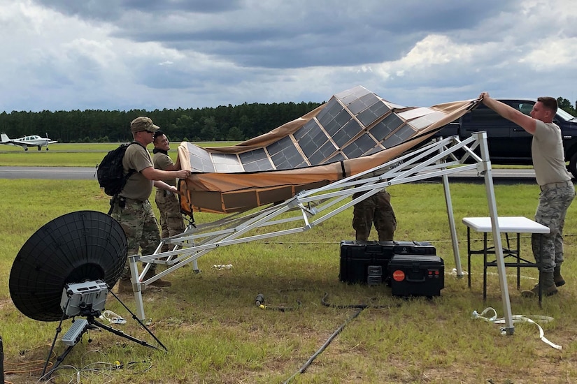 Airmen spread out a tarp covered with solar panels.