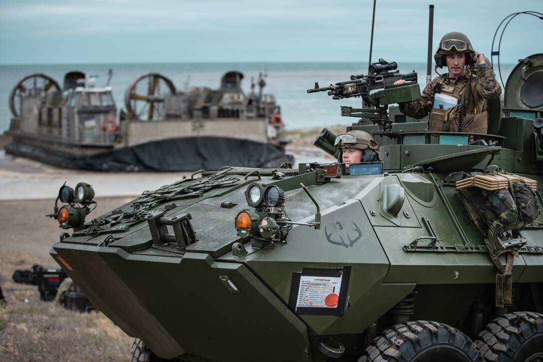 Marines aim weapons from a military vehicle.