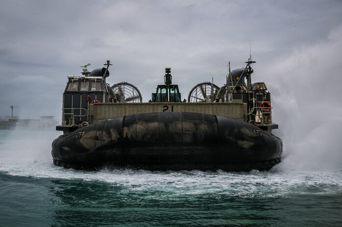 A U.S. Naval Landing Craft Air Cushion (LCAC) maneuvers into the ocean from Port Operations, Naval Base White Beach, Okinawa, Japan, June 1, 2021. Marines from 3d Marine Logistics Group (MLG) and Sailors from Naval Beach Unit (NBU) 7 integrated to load and transport personnel and equipment in support of exercise Poseidon’s Watchtower. NBU-7 is an operational, forward deployed unit that directly contributes to the core capabilities of U.S. Maritime Sea Power by facilitating the movement of troops, equipment, vehicles and supplies from amphibious shipping across the beach. 3d MLG, based out of Okinawa, Japan, is a forward deployed combat unit that serves as III MEF’s comprehensive logistics and combat service support backbone for operations throughout the Indo-Pacific area of respons