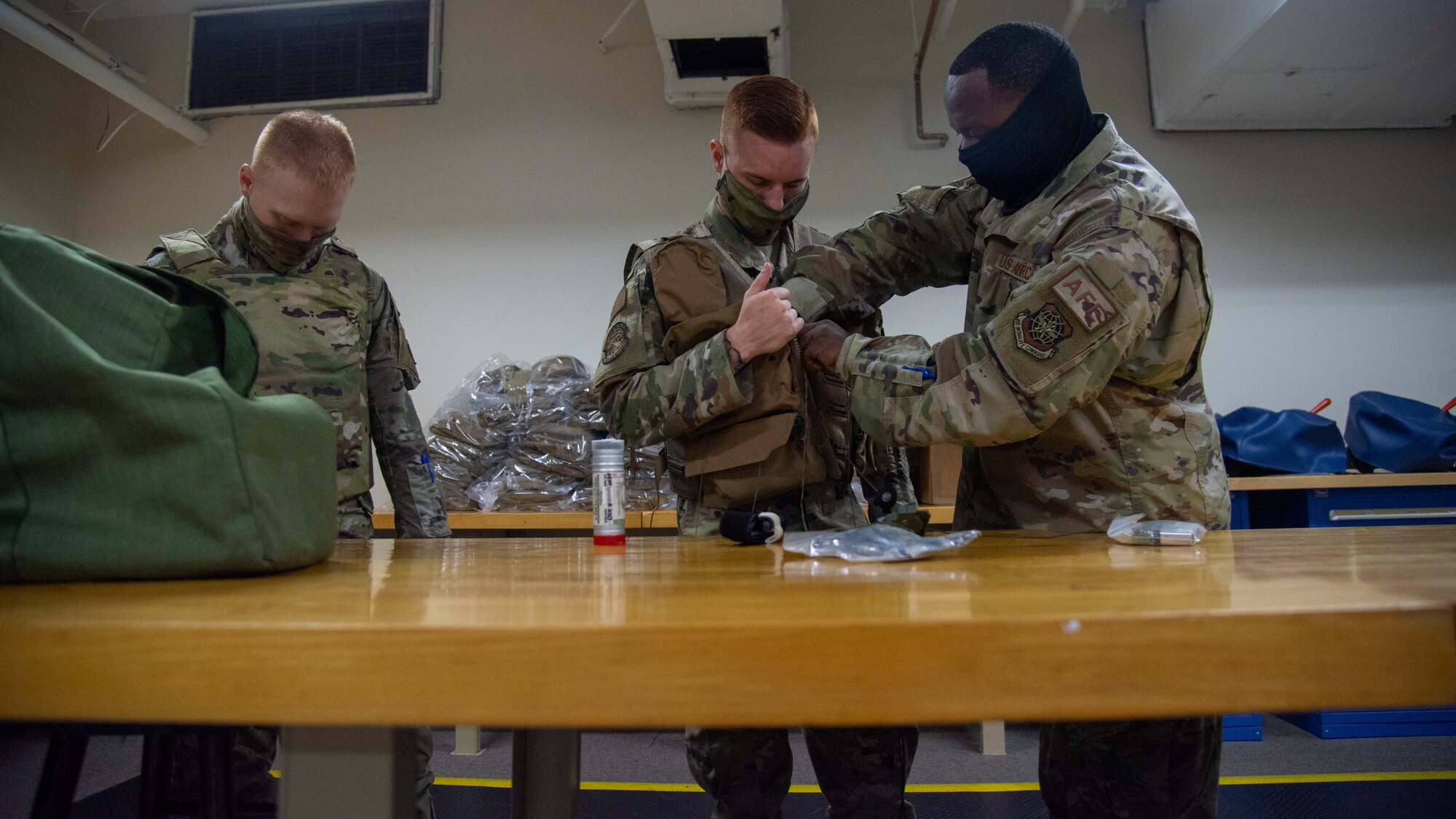 U.S. Air Force Tech. Sgt. Chris Battle, 6th Operations Support Squadron (OSS) Aircrew Flight Equipment (AFE) NCO in charge of aircraft operations (right) inspects a vest worn by Airman 1st Class Daunte Morrison, 6th OSS AFE journeyman (middle) while Airman Nikolai Wroblewski, 6th OSS AFE apprentice (left) waits for his vest inspection at MacDill Air Force Base, Florida, April 14, 2021. 6th OSS AFE members must be fully trained on lifesaving equipment and survival components as well as keep air crews trained and proficient on the use of such equipment.