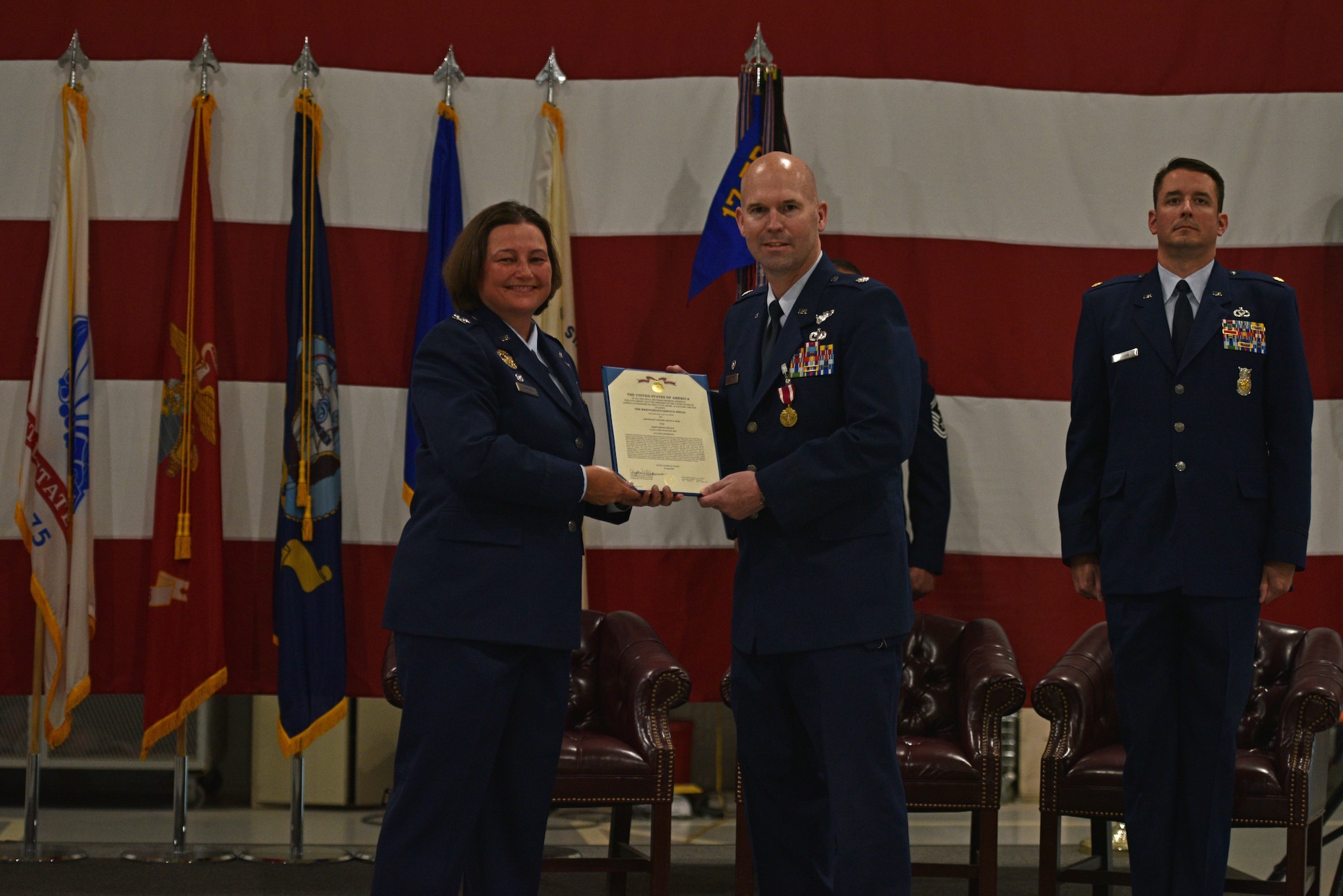 U.S. Air Force Col. Angelina Maguinness, 17th Training Group commander, presents Lt. Col. Kevin Boss, 312th Training Squadron outgoing commander, the certificate for Boss’s Meritorious Service Medal during the change of command ceremony at the Louis F. Garland Department of Defense Fire Academy High Bay on Goodfellow Air Force Base, Texas, June 1, 2021. Boss was decorated for leading major planning efforts to combat COVID-19 while ensuring safety and the quality of fire protection in technical applications training. (U.S. Air Force photo by Senior Airman Ashley Thrash)