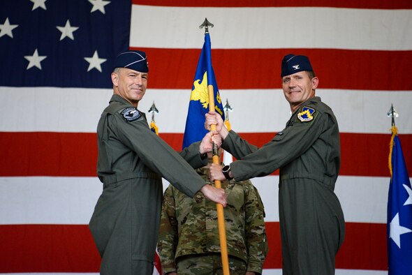 Two commanders hold a guidon during a ceremony.