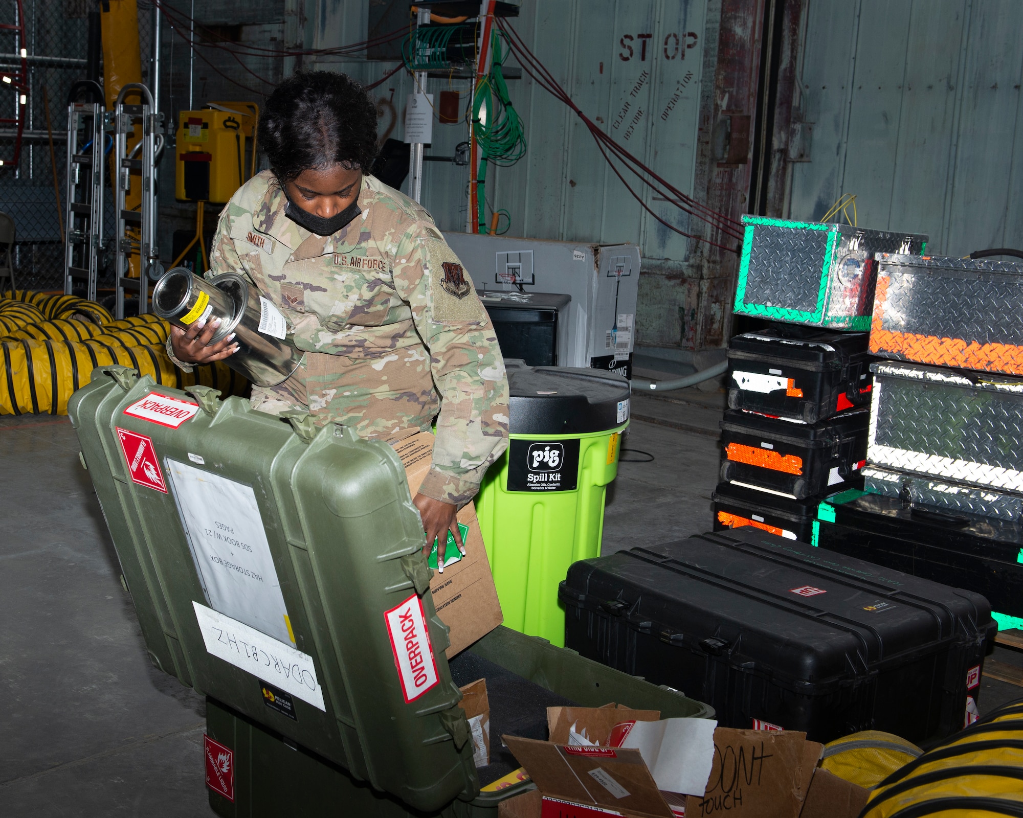 female Airman packing packaged materials inside a medium sized green storage case