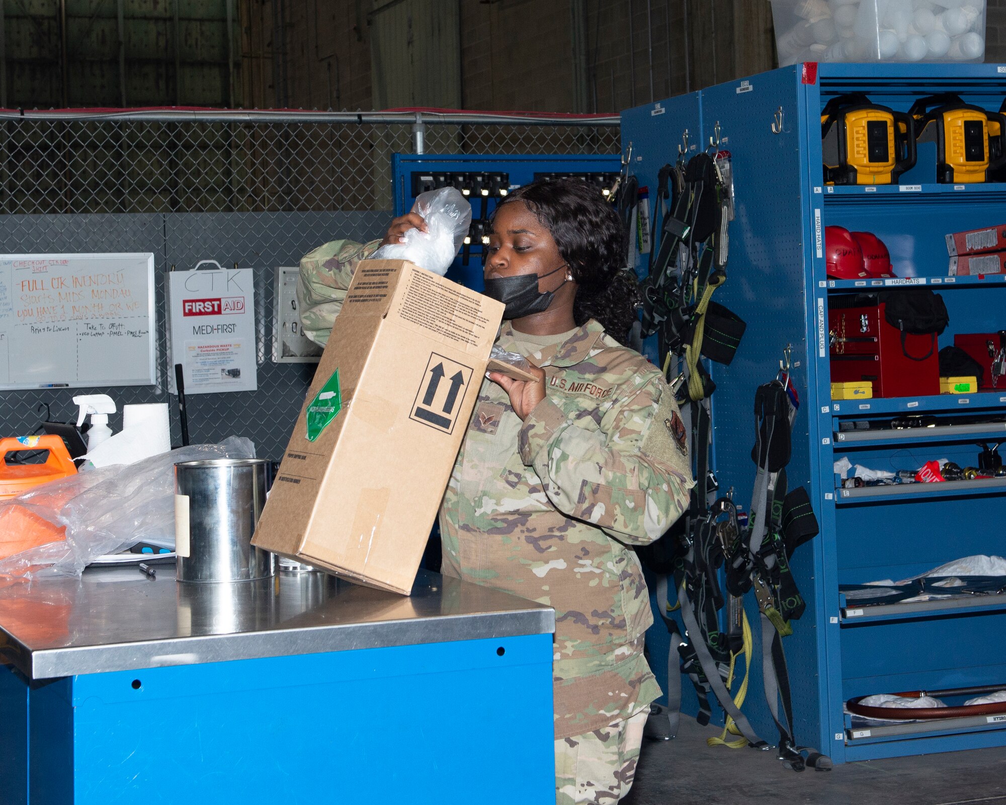 female Airman packaging bubble wrapped can inside box labeled non flammables