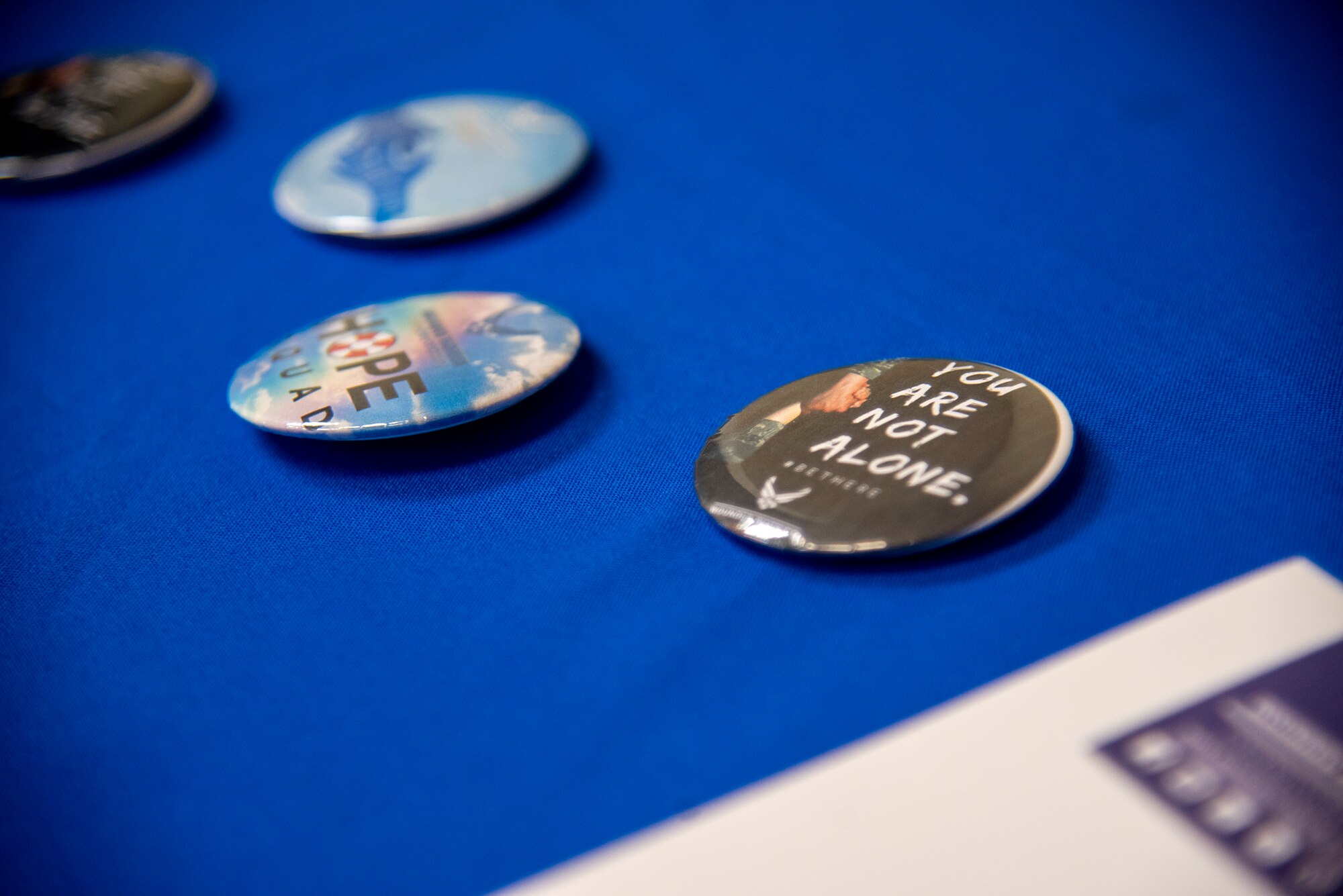 Four buttons with suicide prevention messaging sit on a presentation table during an Applied Suicide Intervention Skills Training (ASIST) course, led by Air Force Wounded Warrior Program (AFW2) leaders, at MacDill Air Force Base, Florida, May 12, 2021. Suicide prevention and Airmen’s resiliency remain a top priority for the U.S. Air Force and Team MacDill.