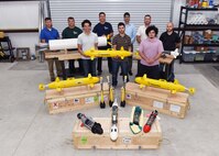 Lead scientists and engineers from Naval Sea Systems Command Warfare Center Divisions pose for a photo as a representation of a collaborative and innovative effort in development of modular, inexpensive unmanned systems collectively known as the “microSwarm Family of Systems,” or “µFOS."