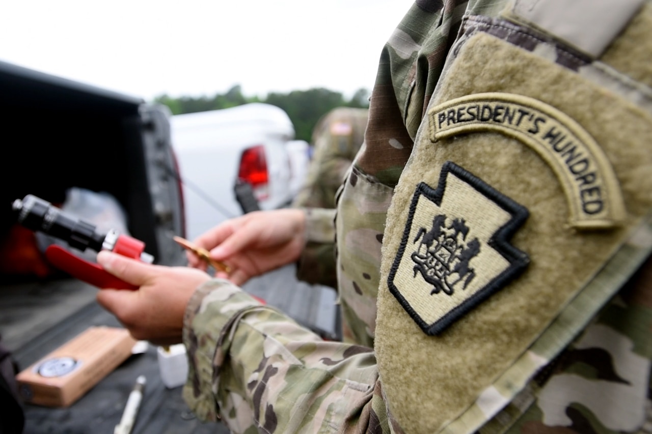 A soldier handles ammunition at an outdoor range.