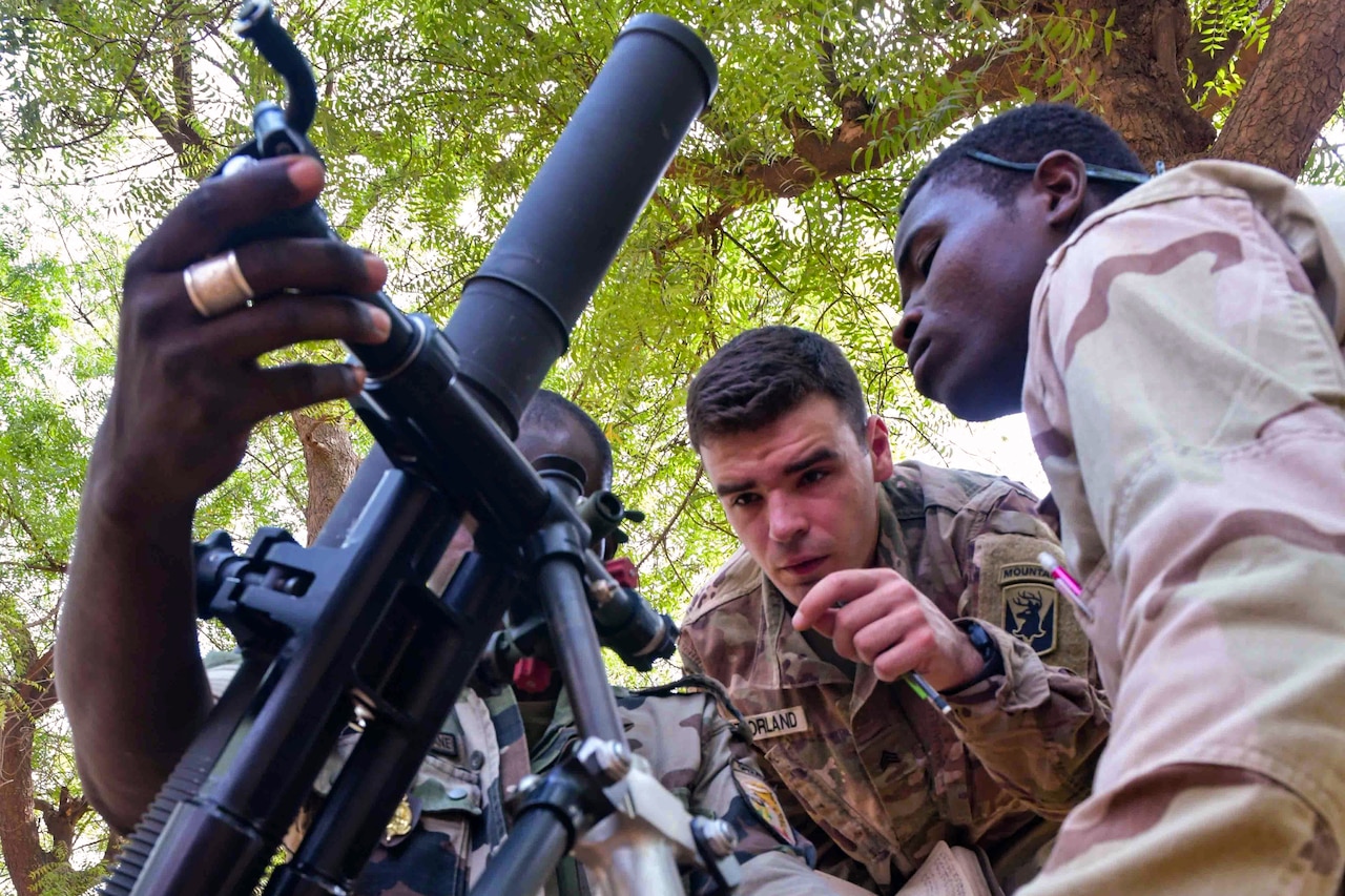 A soldier shows other soldier how to use a gun.