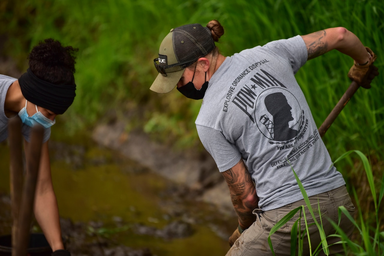 An airmen digs in a forest.