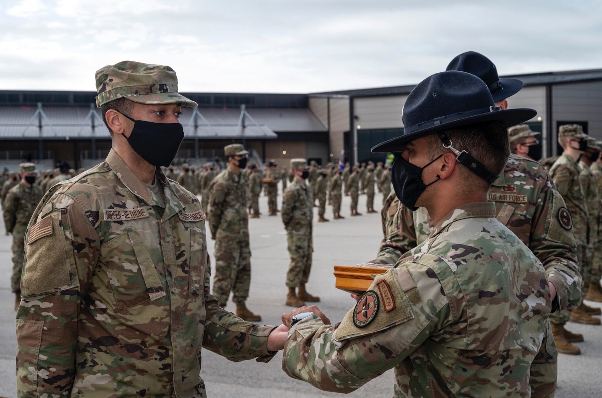 A trainee receives an Airmen's coin from a Military Training Instructor.