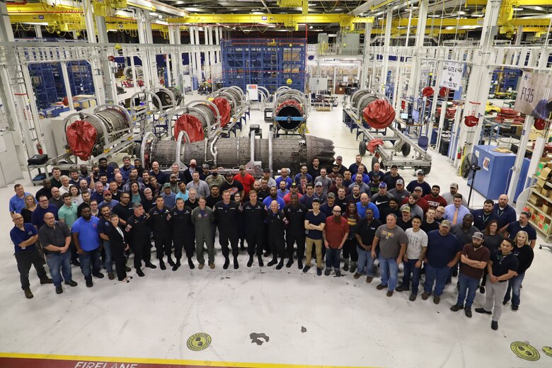Group of people standing in front of an aircraft engine