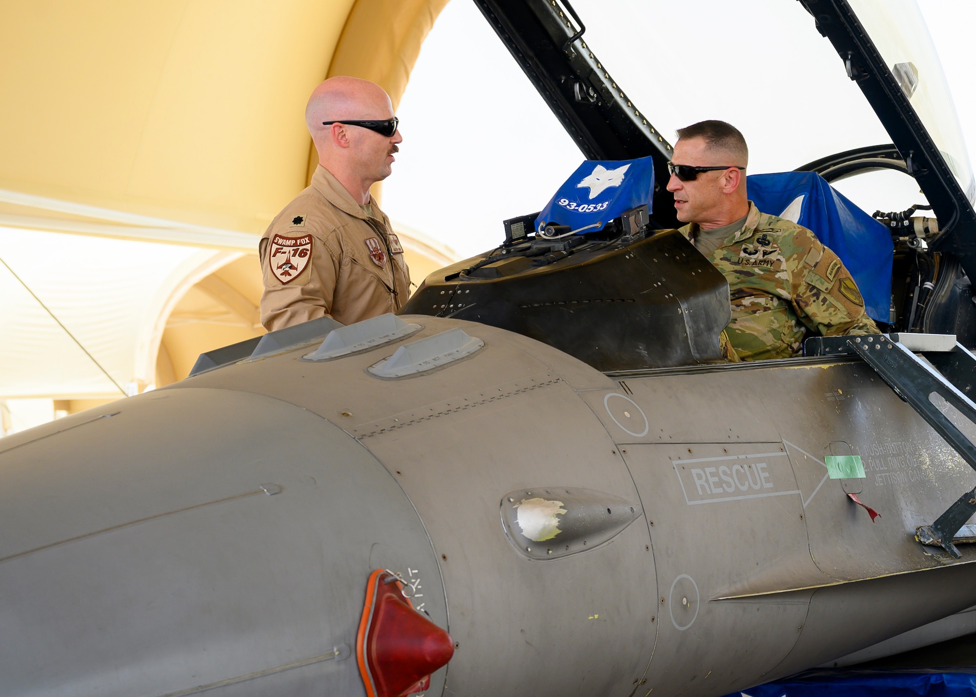 Sgt. Maj. John Ferrante Jr., U.S. Central Command forward senior enlisted leader in the Kingdom of Saudi Arabia, sits in the cockpit of an U.S. Air Force F-16CJ Fighting Falcon, while Lt. Col. Justin Puro, 378th Expeditionary Operations Group deputy commander, explains the aircraft, Prince Sultan Air Base, KSA, May 26, 2021. Several U.S. generals from across the region and their staff visited units at PSAB, meeting with various personnel to learn about defense efforts and expanding capabilities on base. (U.S. Air Force photo by Senior Airman Samuel Earick)