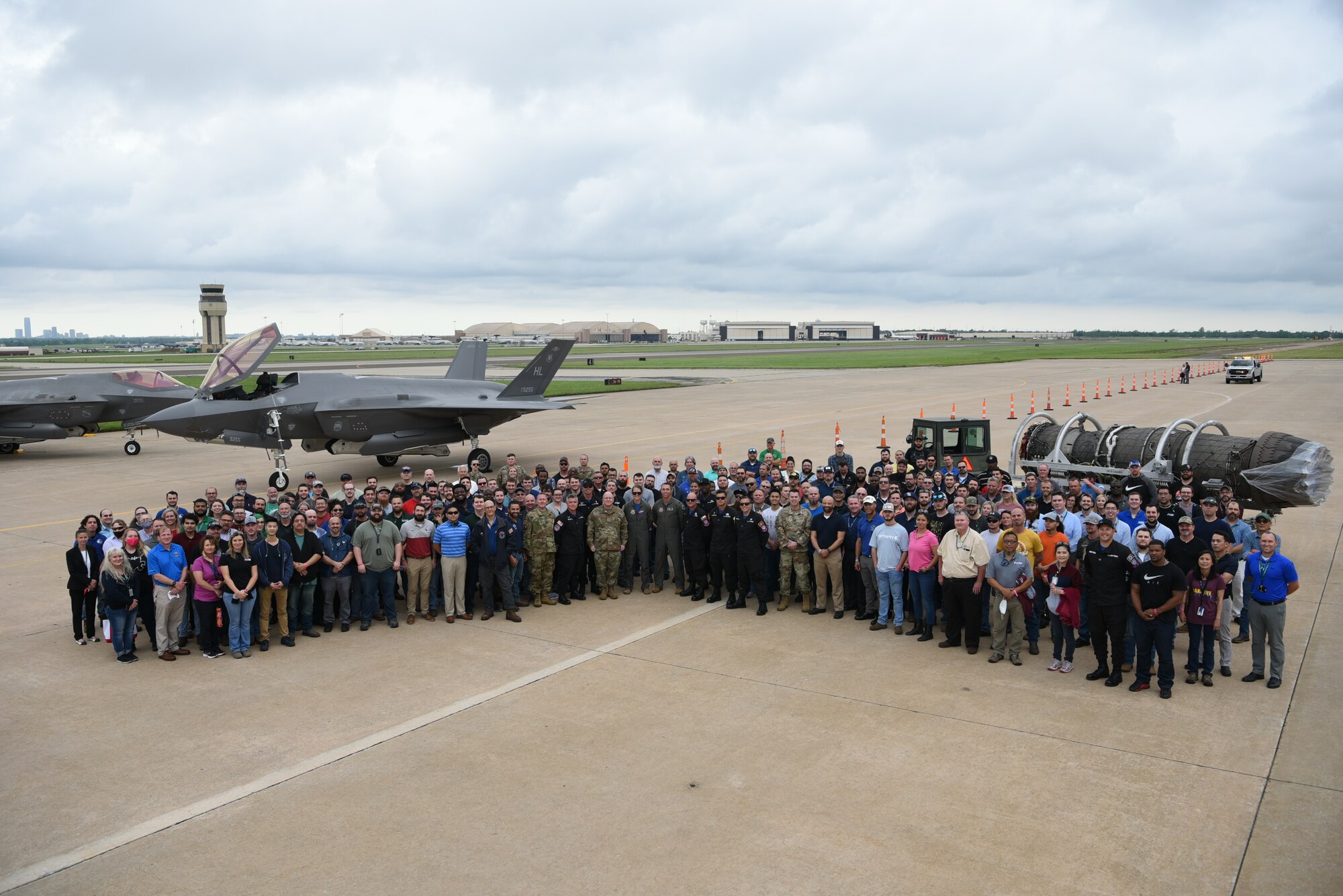 Group of people standing in front of an aircraft and an engine.