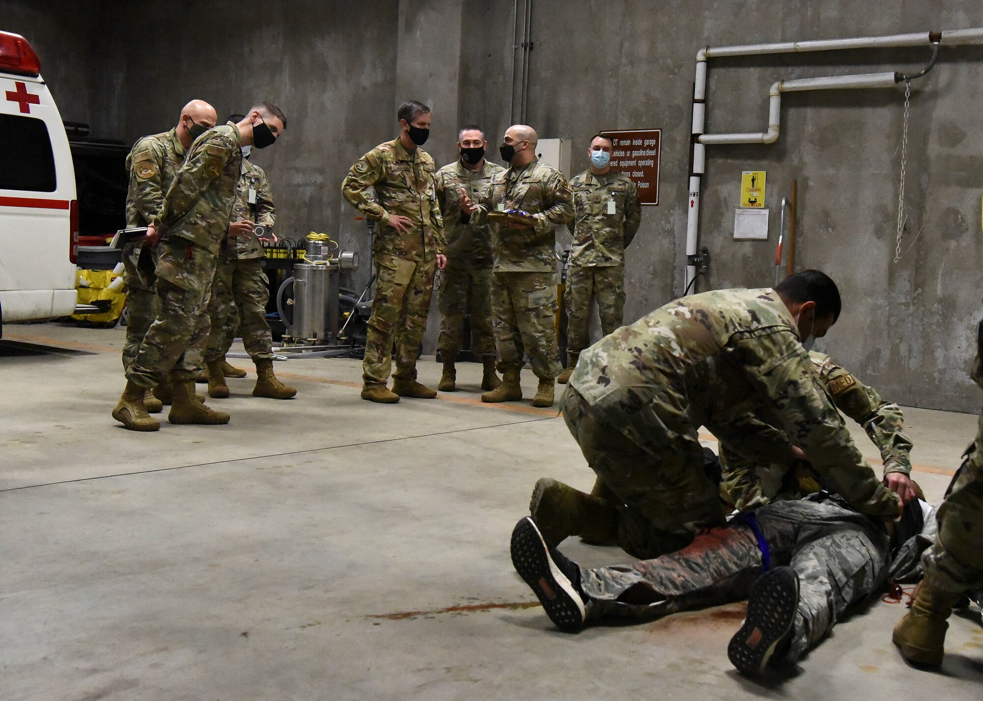 Military members work on an acting victim in front of an audience of military members.