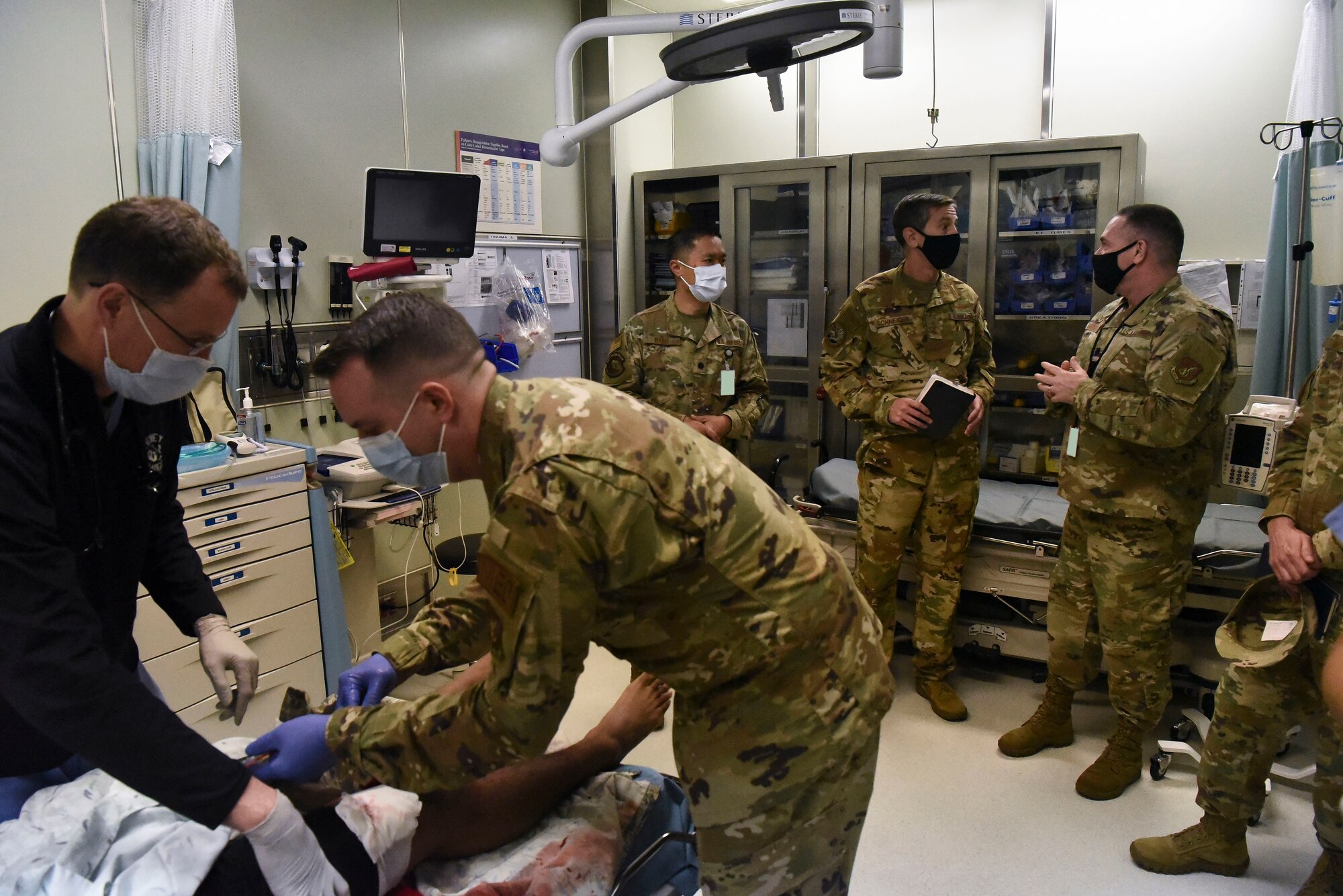 Military doctors tear off an acting victims prop uniform in an urgent care clinic.