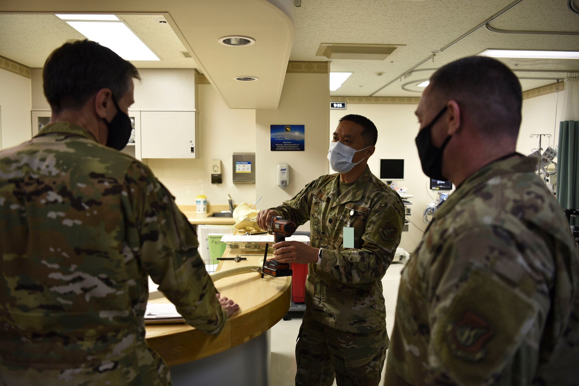 A man in uniform shows another man in an uniform a drill.