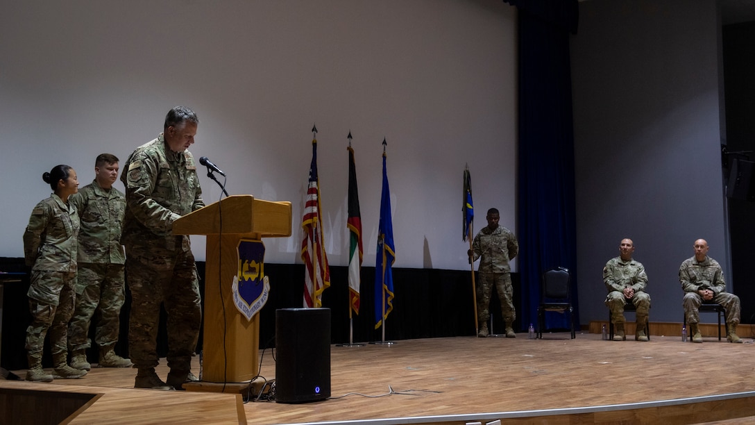 Man in uniform speaks on stage, standing behind a podium.