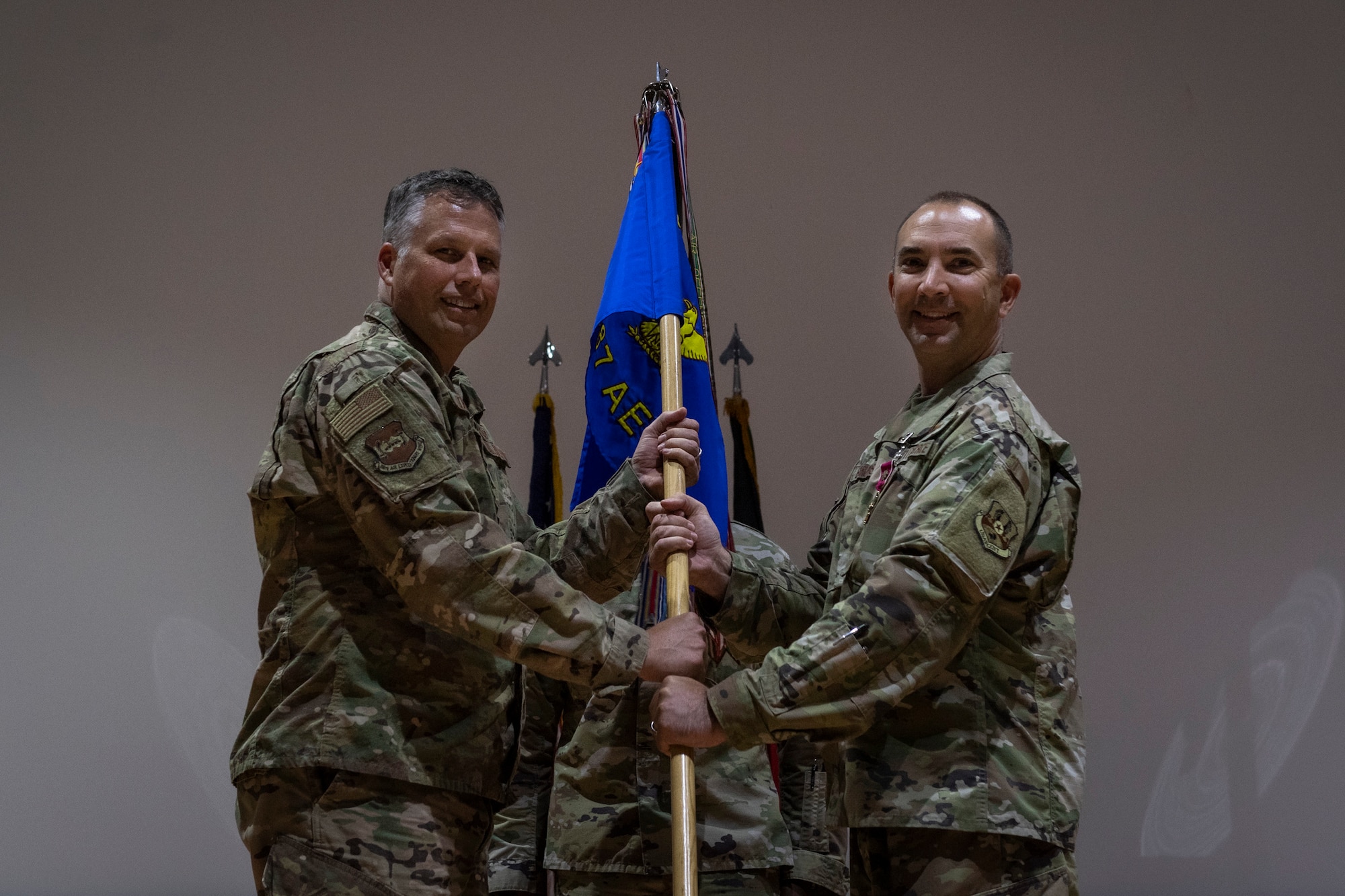 Two people stand holding a guidon.