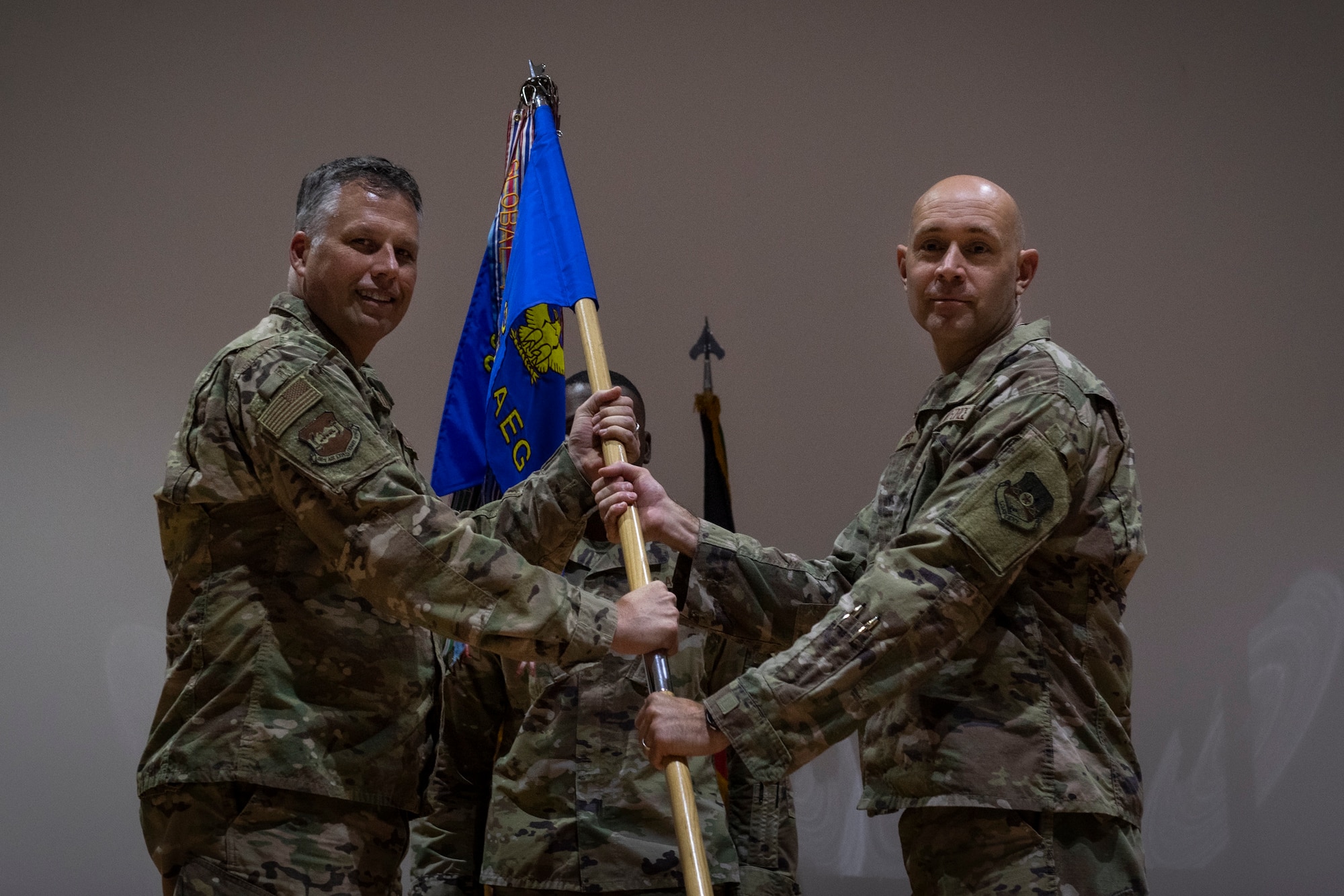 two people stand on stage holding a guidon.