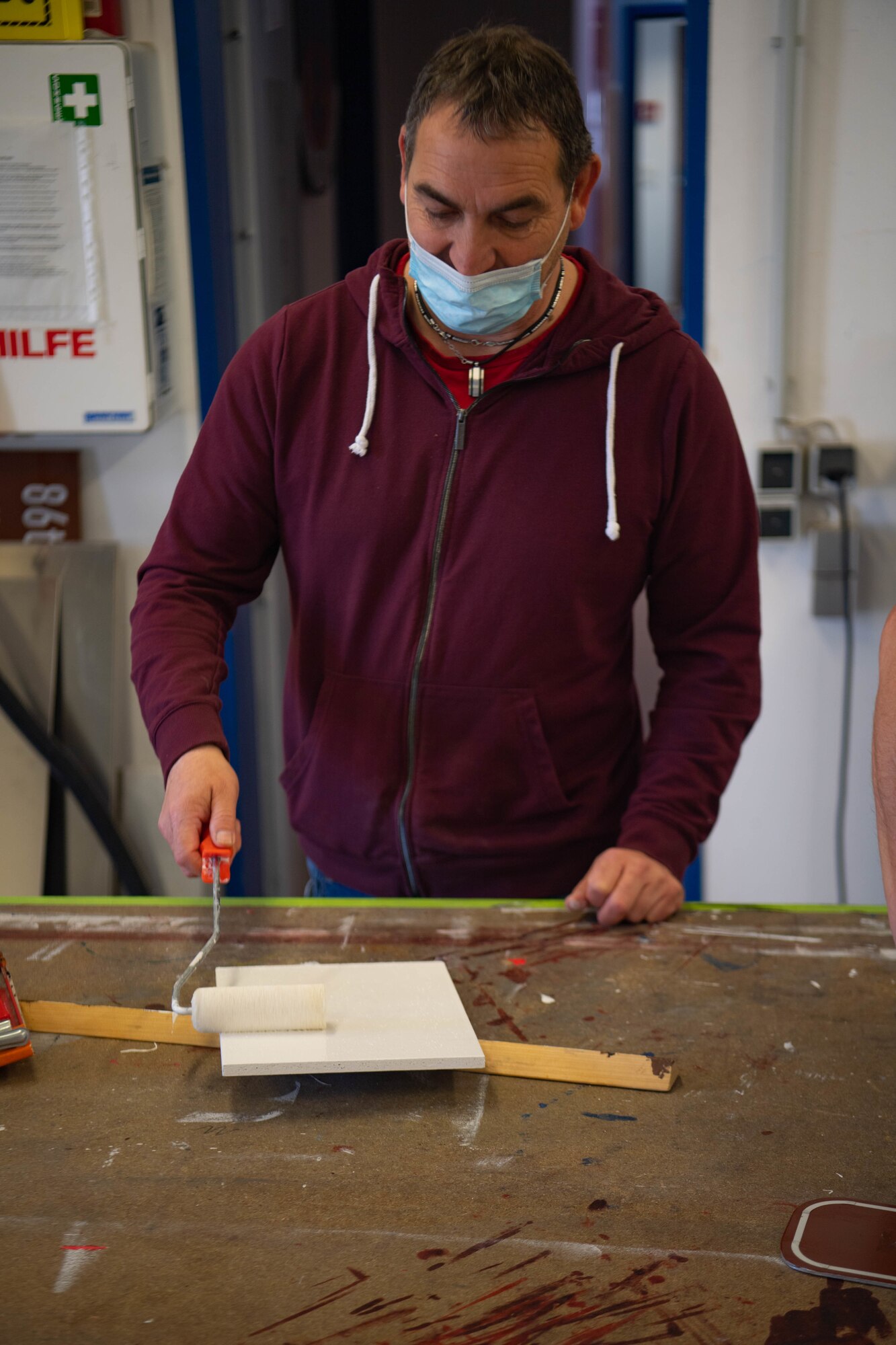 Michael Heinz paints a wooden board white.