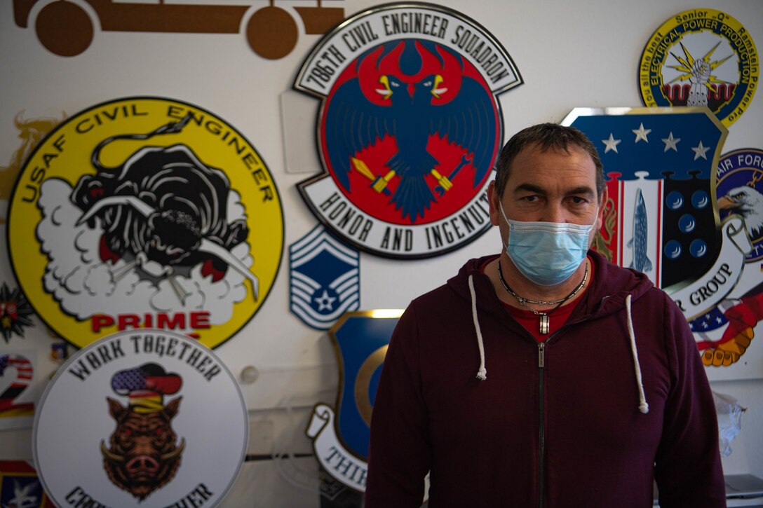 Michael Heinz stands by signs that he created at the paint and sign shop at Ramstein Air Base.