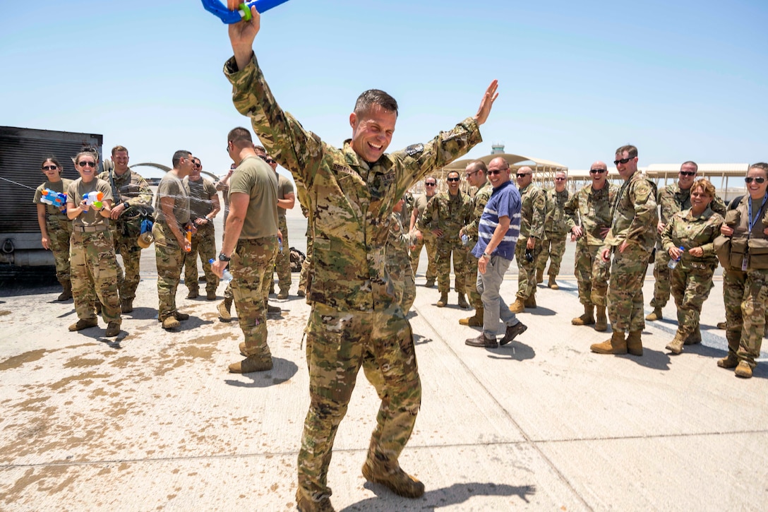 An airmen gets sprayed with water surrounded by other service members.