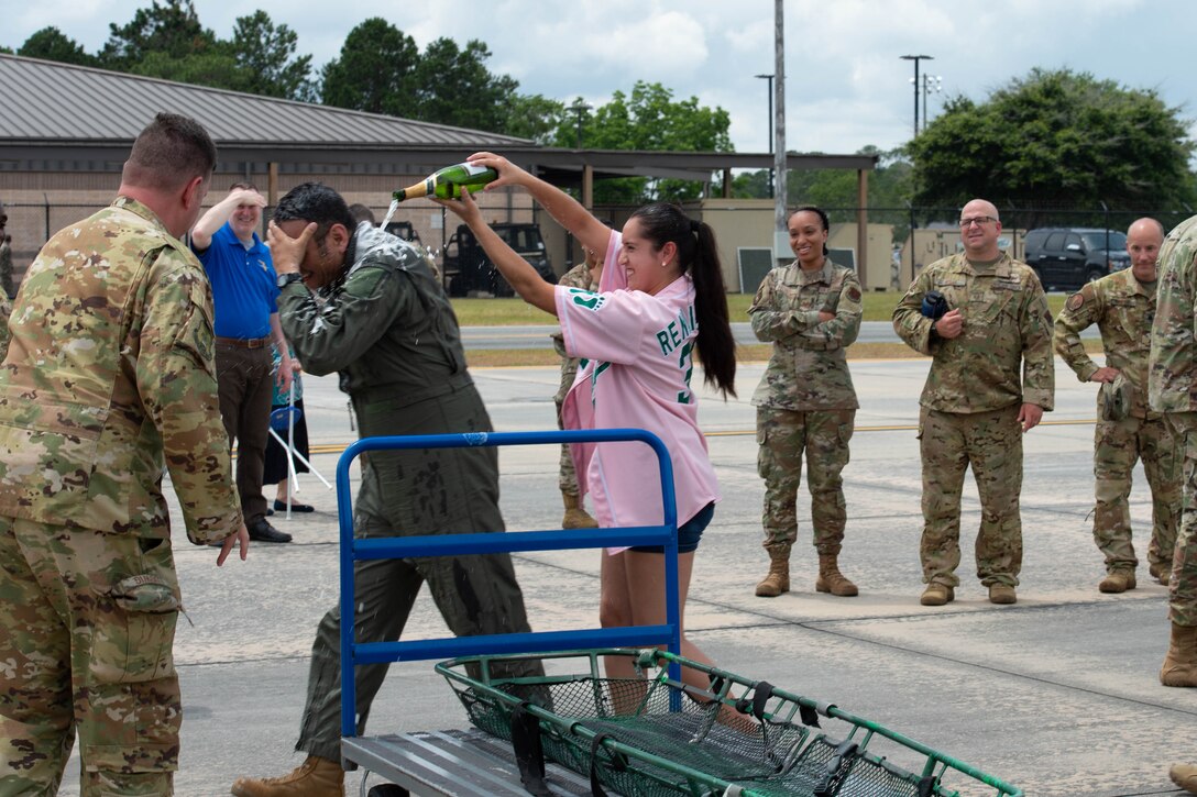 A photo of a girl pouring champagne on an Airman.