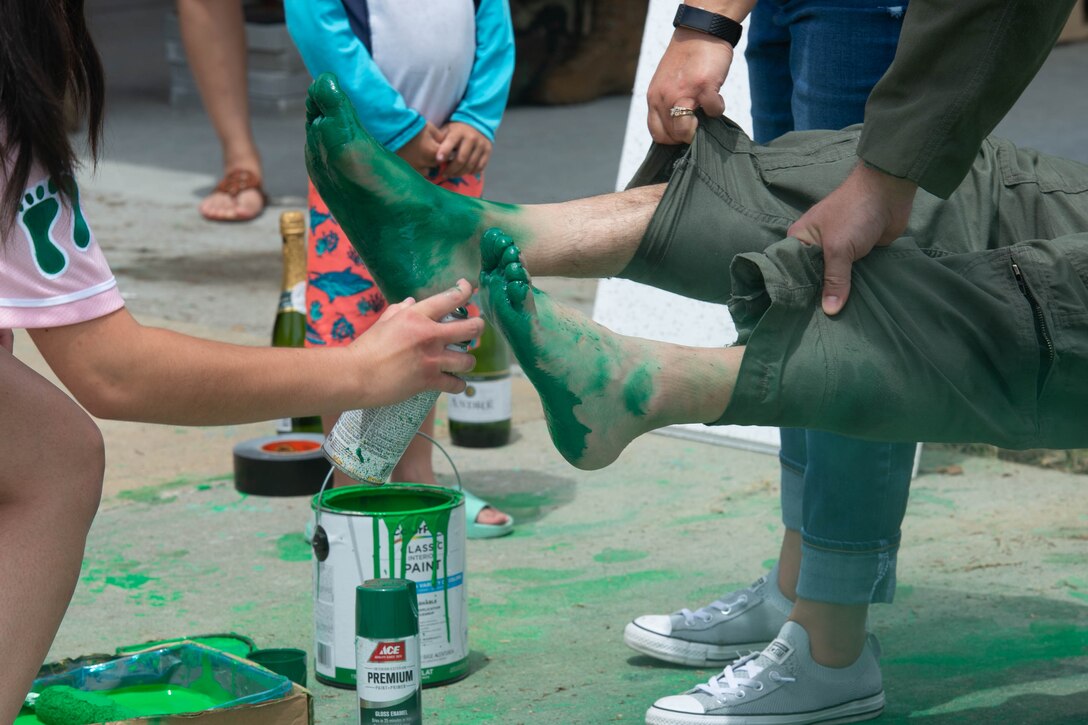 A photo of a girl painting an Airman's feet.
