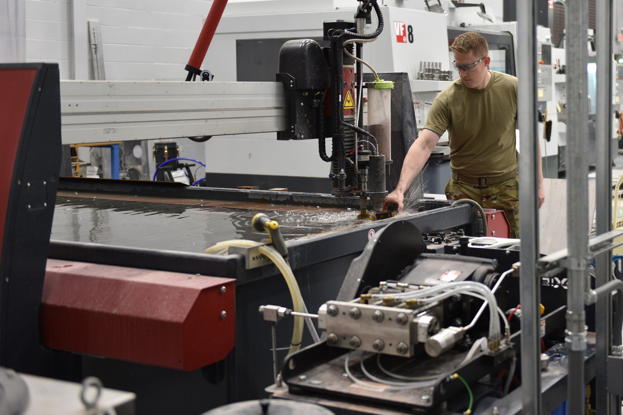 Master Sgt. Michael Howard, aircraft metals technician of the 911th Maintenance Squadron fabrication flight, makes adjustments to a metal hold-down block during the calibration process of the water jet cutting tool at the Pittsburgh International Airport Air Reserve Station, March 10, 2021.