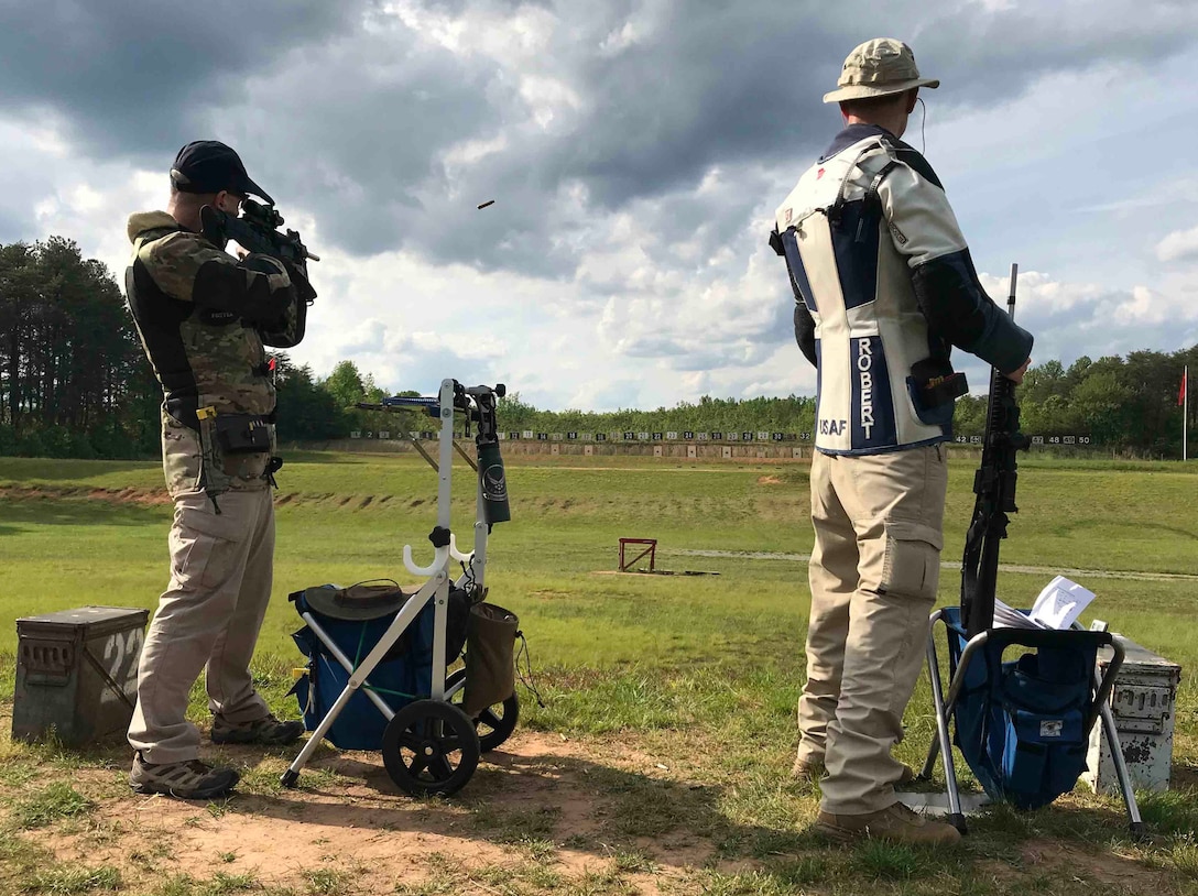 Office of Special investigations Special Agent Sean Foster, left, fires down range as fellow OSI SA Robert Davis looks on during the 59th Annual Atlantic Fleet and All Navy (East) Rifle and Pistol Championships at Marine Corps Base Quantico, Va., May 15-22, 2021. The Air Force Shooting Team tandem earned Navy Marksmanship Expert ribbons for their exceptional performances during the week. (Photo by Lt. Col. Mark Gould)